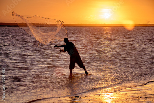 Fisherman throwing a cast-net at sunset. photo