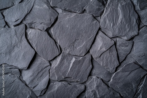 A textured gray stone wall with irregularly shaped slate pieces arranged closely together, creating a rustic and natural appearance.