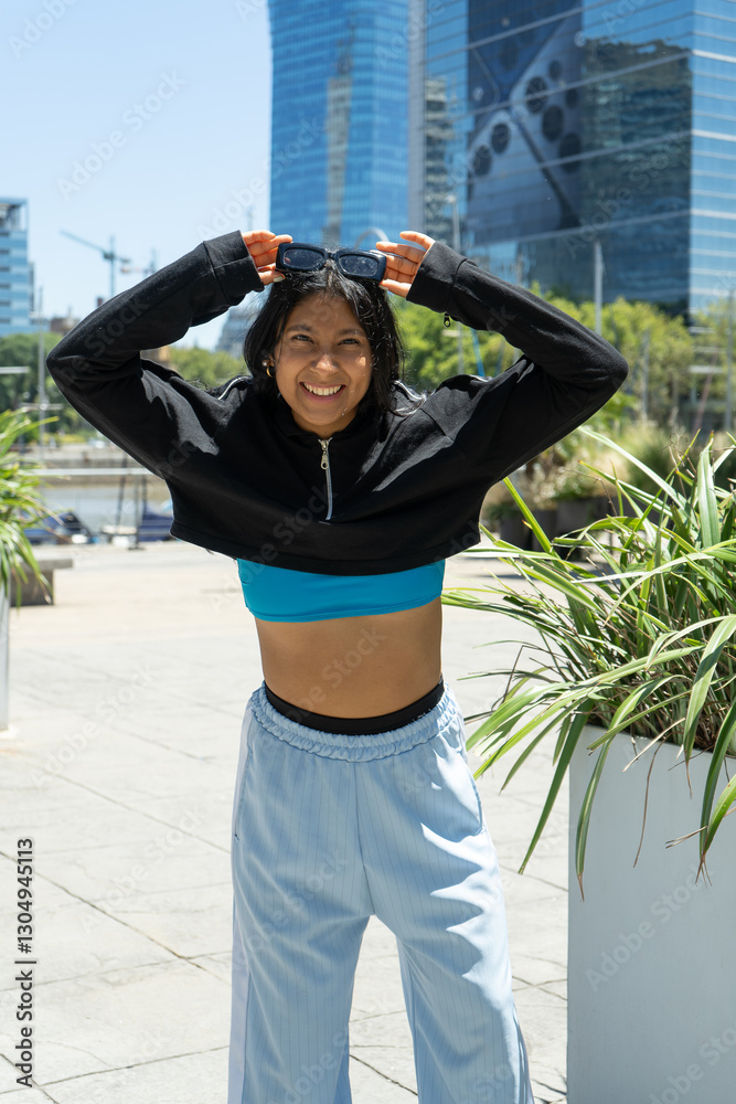 Fototapeta premium Young latin woman putting sunglasses on head, urban fitness concept