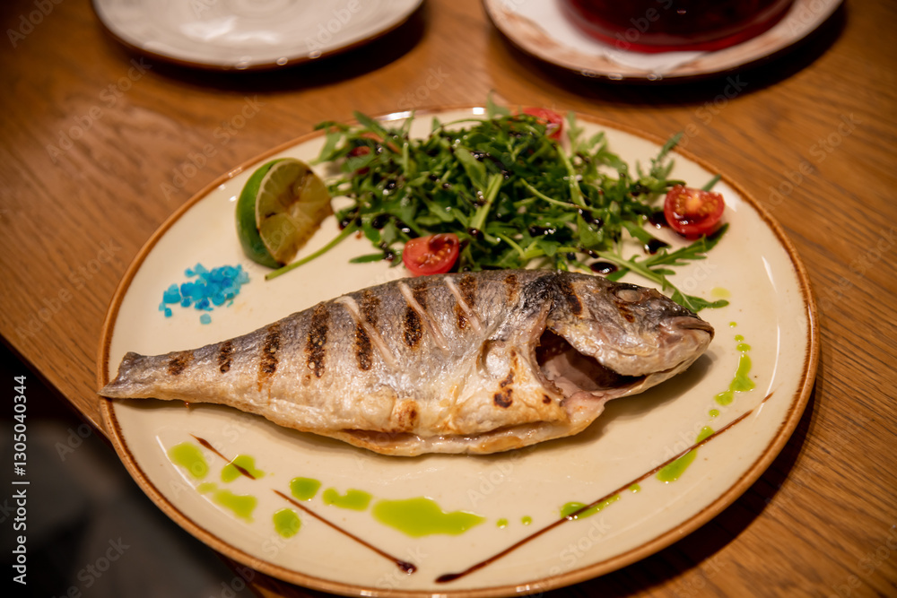 Grilled fish served with fresh salad and lime at a cozy cafe Grilled fish served with fresh salad and lime at a cozy cafe