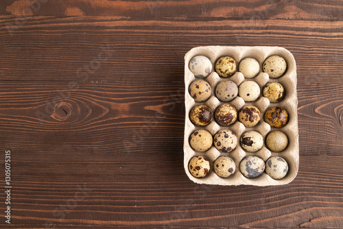Pile of raw quail eggs on brown wooden background. top view, copy space.