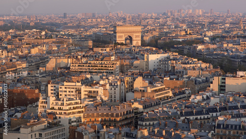 Vue panoramique des toits parisiens au coucher du soleil, avec une terrasse verdoyante