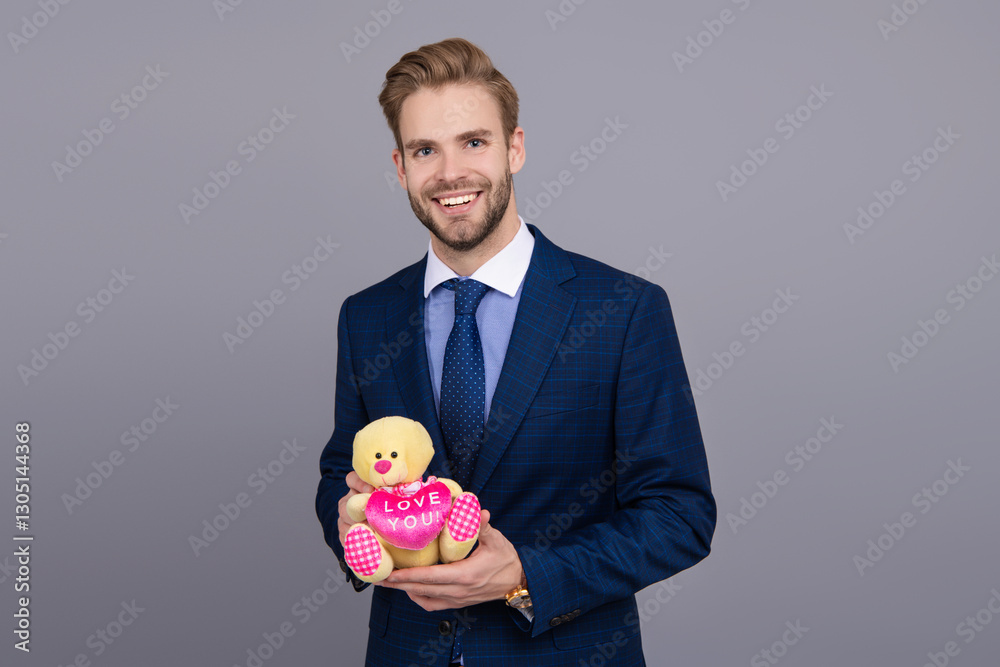 Business man with corporate gift isolated on grey. Corporate present. Successful boss hold gift toy. Valentines day. Businessman prepare for romance date. Secret valentine at business corporate Business man with corporate gift isolated on grey. Corporate present. Successful boss hold gift toy. Valentines day. Businessman prepare for romance date. Secret valentine at business corporate