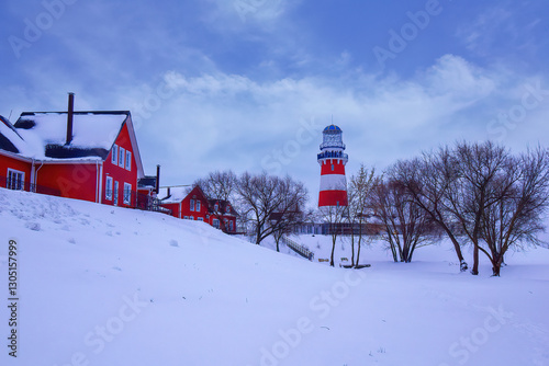 lighthouse and bright houses near a snow-covered pond
