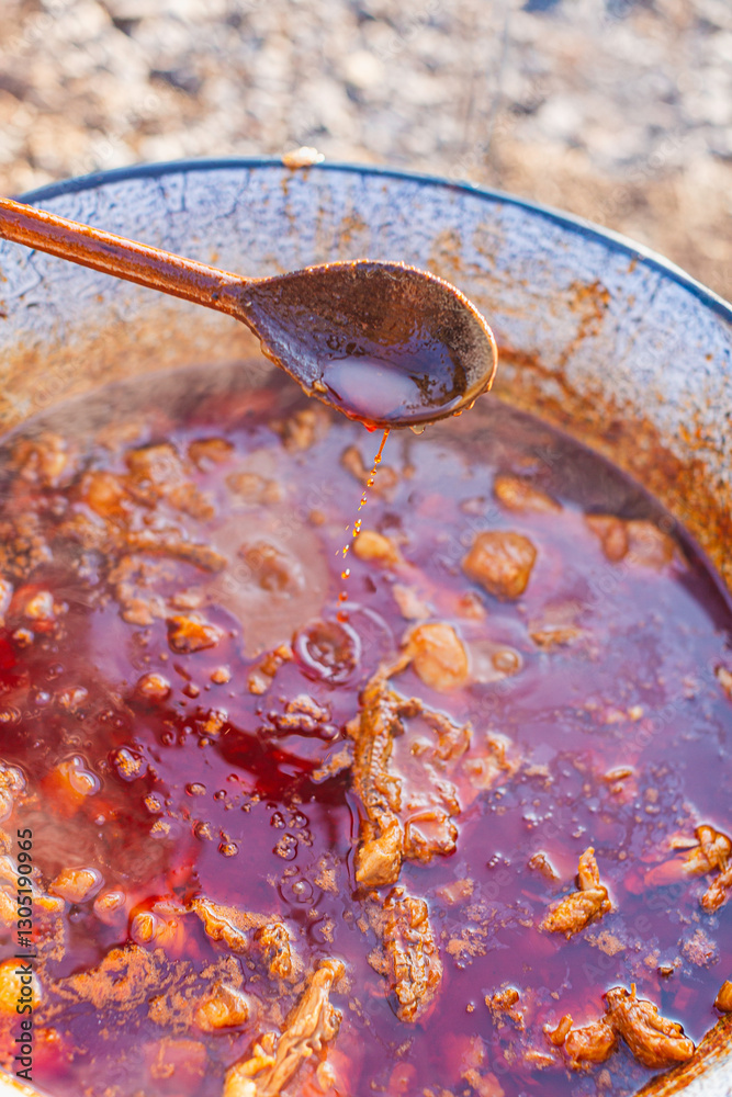 Fototapeta premium Cooking Traditional Stew in a Rustic Pot with Wooden Spoon Outdoors