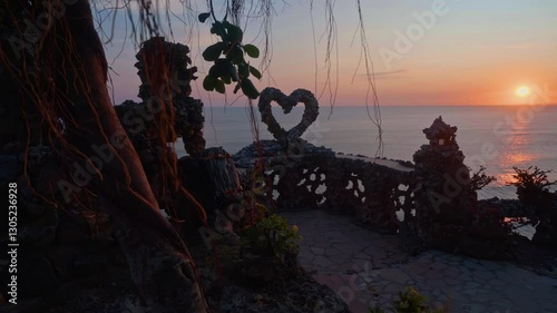 First-person view, a person's hands push the branches of a tree apart, revealing a picturesque observation deck over the ocean against the backdrop of sunset photo