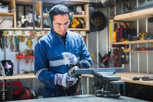 Latin worker grinding metal in workshop wearing safety gear