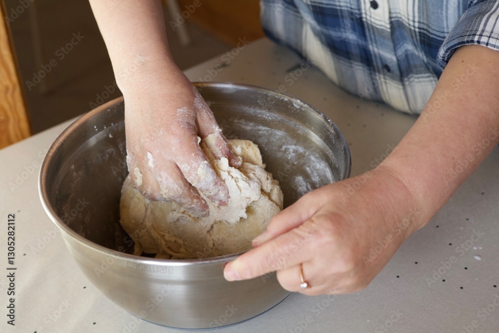 Fototapeta premium girl kneading dough with her hands in a metal bowl