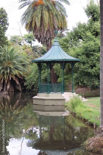 Reflective Pond with Gazebo and Palm Tree in a Natural Garden Setting