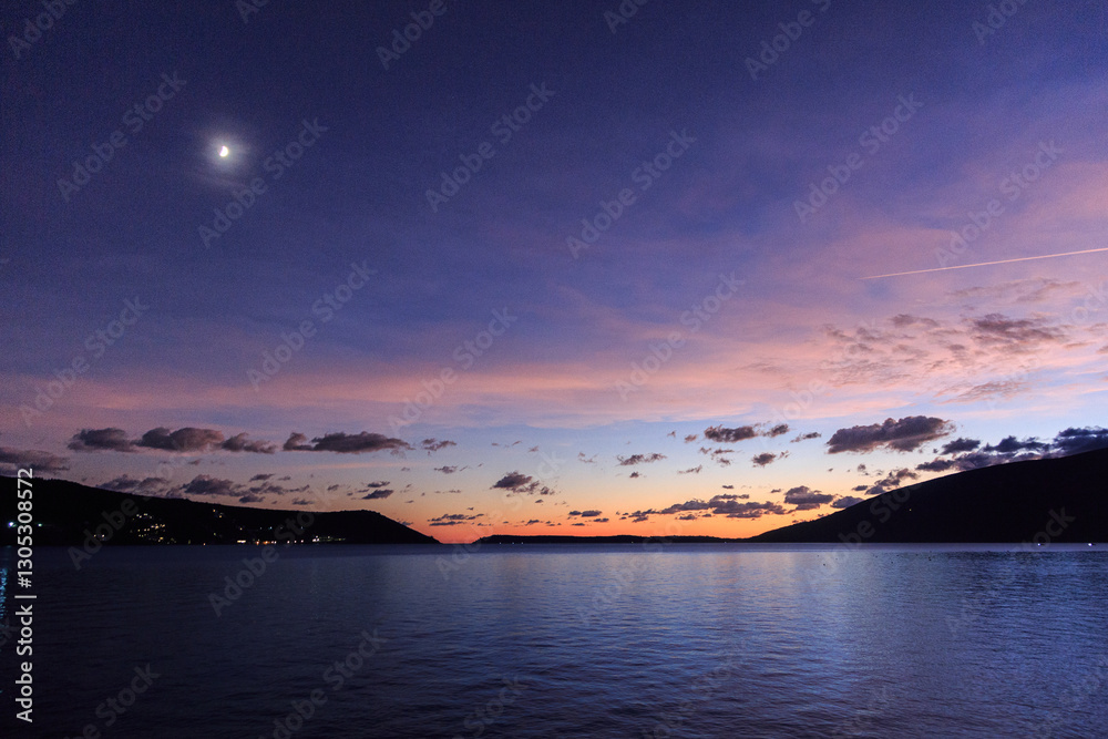 Fototapeta premium captures a breathtaking sunset over a tranquil body of water