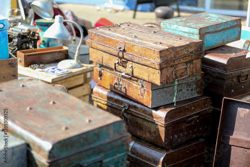 Lively flea market scene in France with vintage items, antiques, books, and decorations. People browsing and enjoying the atmosphere on a sunny day. European market culture captured in detail.