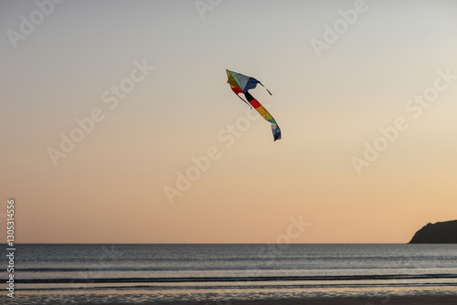 flying a kite at the beach during sunset. Warm evening light, calm sea, and joyful holiday mood create a peaceful and nostalgic summer scene.