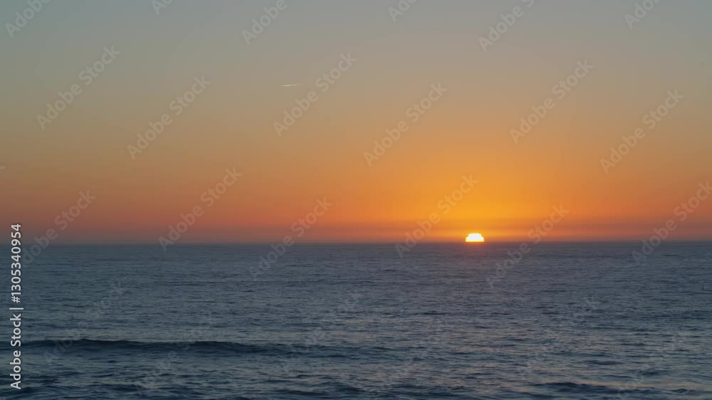 Sun slowly sinks below the ocean horizon casting golden-orange glow across sky Gentle waves ripple under fading light creating a serene and tranquil atmosphere. Concept peaceful nature and relaxation Sun slowly sinks below the ocean horizon casting golden-orange glow across sky Gentle waves ripple under fading light creating a serene and tranquil atmosphere. Concept peaceful nature and relaxation