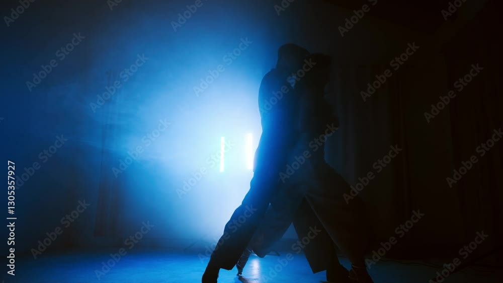Under red and orange lights, a tango instructor and student bring the stage to life with rhythmic movements. Their silhouettes reflect the elegance and passion of the dance.
Under red and orange lights, a tango instructor and student bring the stage to life with rhythmic movements. Their silhouettes reflect the elegance and passion of the dance.