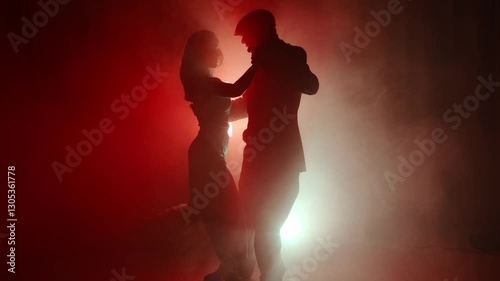 A tango dance instructor and student perform a passionate and elegant routine in the mist. Dramatic lighting enhances the aesthetic and emotional intensity of the dance.