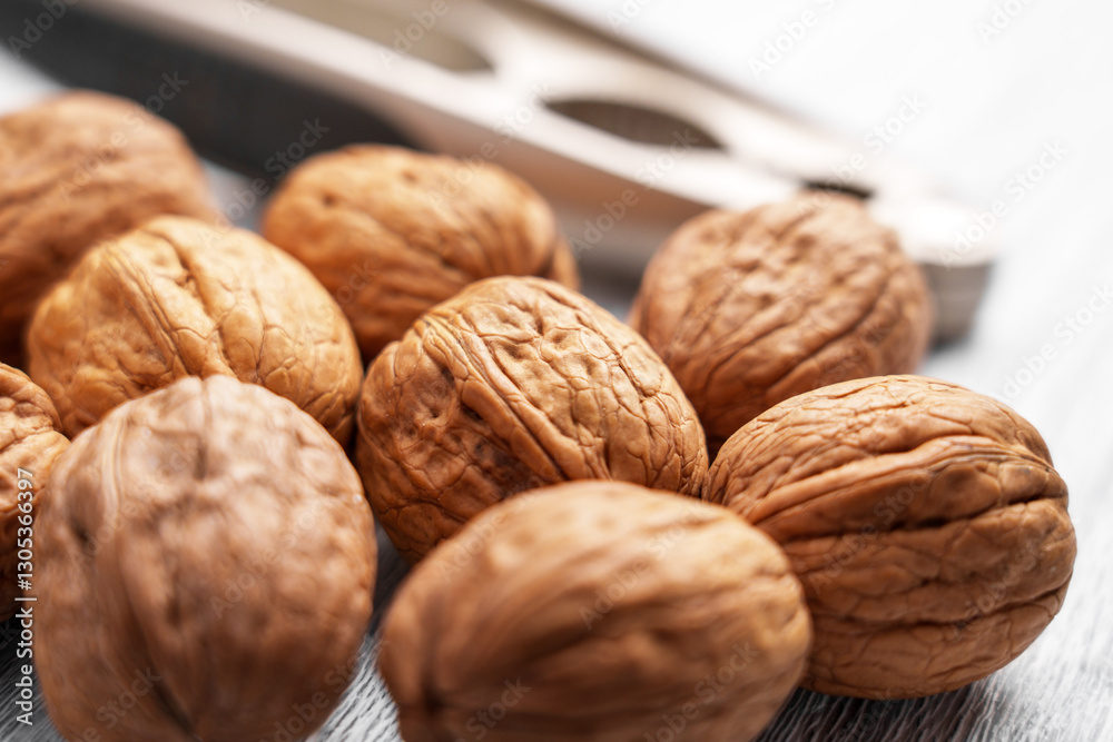 Whole walnuts with a nutcracker. Close-up of textured brown shells. Healthy snack rich in nutrients and omega-3. Selective focus. Whole walnuts with a nutcracker. Close-up of textured brown shells. Healthy snack rich in nutrients and omega-3. Selective focus.