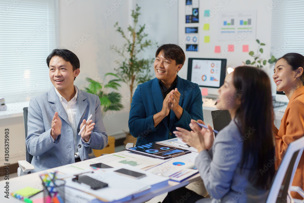 Fototapeta premium Professional Asian business team clapping hands while seated, celebrating successful collaboration in modern corporate meeting space with enthusiastic teamwork