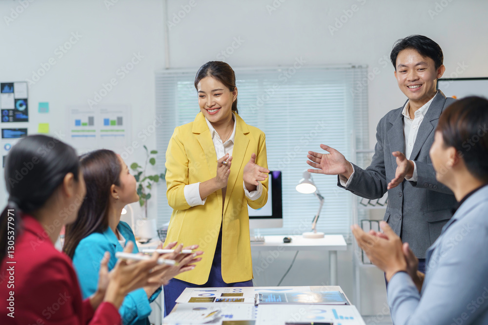 © amnaj - Asian businesspeople clapping hands during a meeting in a modern office, celebrating a successful deal or congratulating a colleague for achieving goals