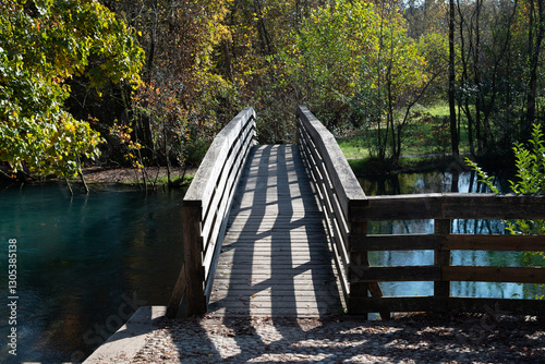 Wooden bridge and railings of a bridge crossing a river. The shadow forms interesting shapes on the surface