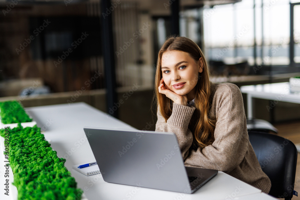 Pensive woman planning working schedule writing in notebook while sitting at working place with laptop Pensive woman planning working schedule writing in notebook while sitting at working place with laptop