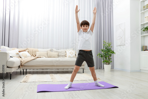Boy doing exercise on fitness mat at home. Sport activity