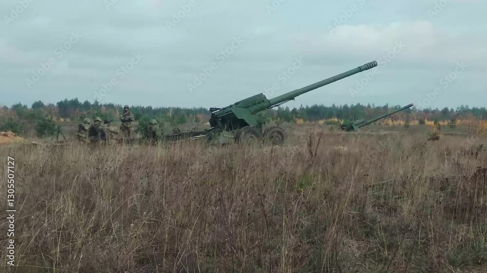 Soldiers and commander fire up an howitzer on the front line in the field. Real shooting of war field with troops, weapons during modern war conflict stage.