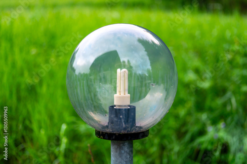 Obraz na płótnie Outdoor light with large glass spheres housing fluorescent bulbs, illuminating the surroundings. In the background, a lush green meadow stretches under the clear sky w salonie
