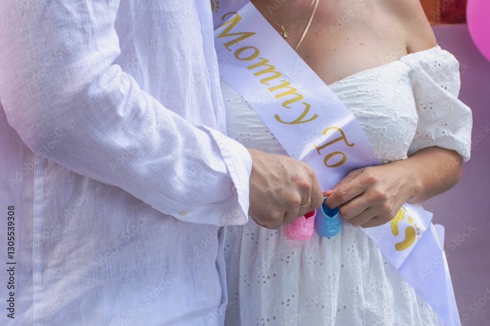 Obraz premium Pregnant woman with sash and baby shoes.