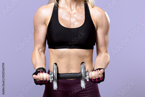 Strength and motivation, losing weight and exercise for arms. Friendly muscular adult lady athlete in sports uniform lifts dumbbell, isolated on violet background, empty space, panorama, studio shot photo