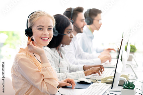 Team of diverse hotline operators with headphones providing service to clients at call center. Young customer support representatives working in telemarketing or telecommunications at modern office