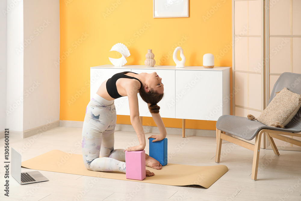 Fototapeta premium Sporty young woman practicing yoga with blocks at home