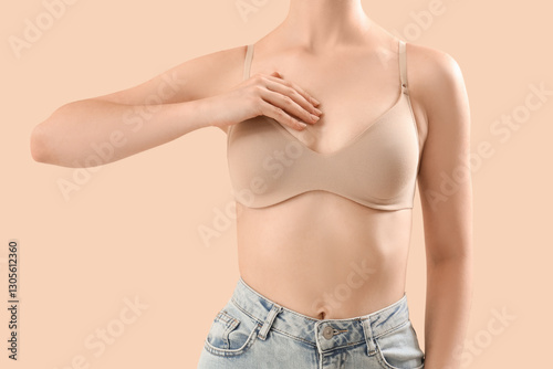 Young woman in bra on beige...