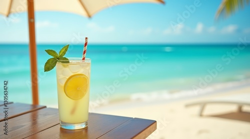 A tall glass of fresh, iced lemonade garnished with a lemon slice and mint leaves sits on a round table at a beachside resort