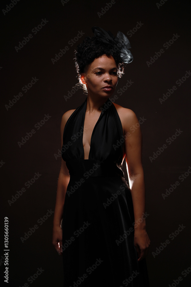 Low key portrait of pretty curly woman in black dress with back light Low key portrait of pretty curly woman in black dress with back light