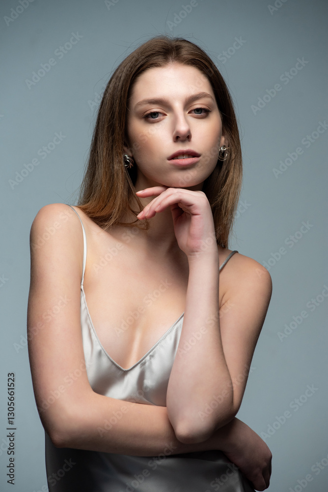 Naklejka premium Elegant woman in a silver satin dress posing stylishly. Accessories include sunglasses and a plaid blazer. Modern, sophisticated, and minimalistic fashion. Neutral background enhances the chic aesthet