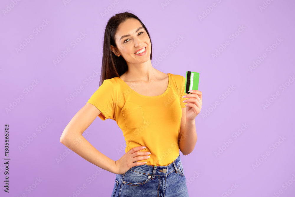 Easy Payment, Banking Concept. Portrait of smiling young female model holding and showing plastic credit card, woman posing isolated over pastel purple studio background. Ecommerce And Shopping. Easy Payment, Banking Concept. Portrait of smiling young female model holding and showing plastic credit card, woman posing isolated over pastel purple studio background. Ecommerce And Shopping.