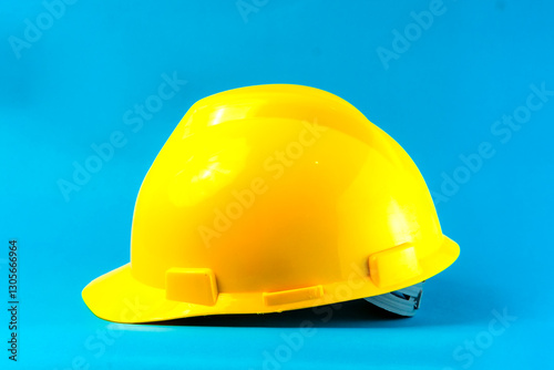 A bright yellow construction hard hat on a blue background. Safety helmet for industrial workers, engineers, and builders, symbolizing workplace protection and occupational safety.