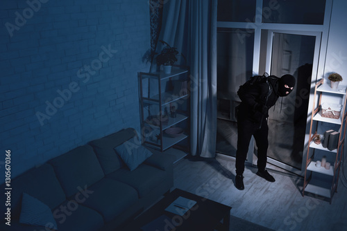 Life After Lockdown. Disguised stealthy robber entering apartment in the dark, holding crowbar, high angle view