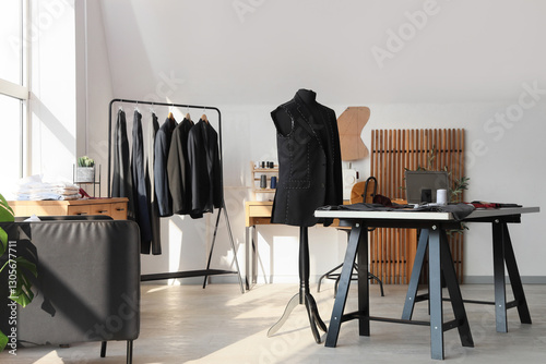 Interior of atelier with tailor's workplace, mannequin and men's clothes