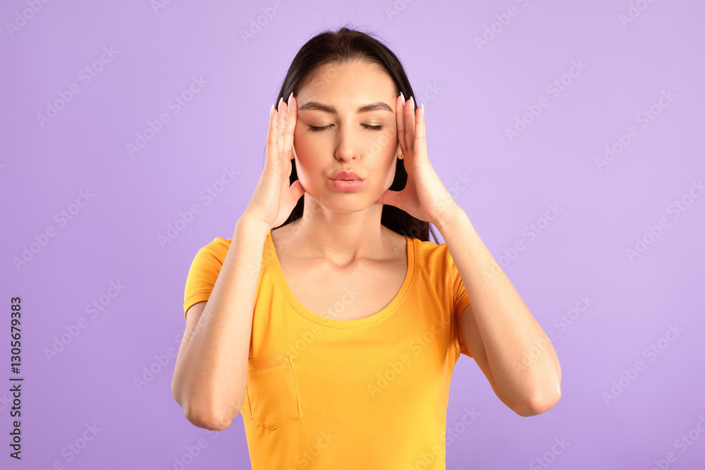 Reducing Stress. Young woman massaging temples with closed eyes, breathing out, trying to calm down, purple studio wall Reducing Stress. Young woman massaging temples with closed eyes, breathing out, trying to calm down, purple studio wall