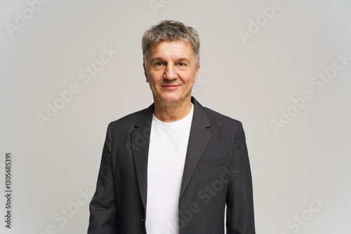 Middle-aged man in a suit jacket with a casual shirt, standing against a neutral backdrop in a studio