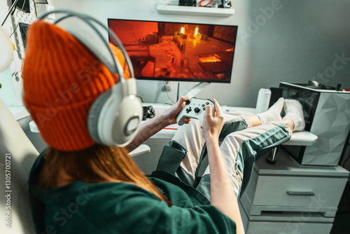 Fotografía Gamer girl with professional headphones relaxing in gaming room playing shooter video game on powerful computer