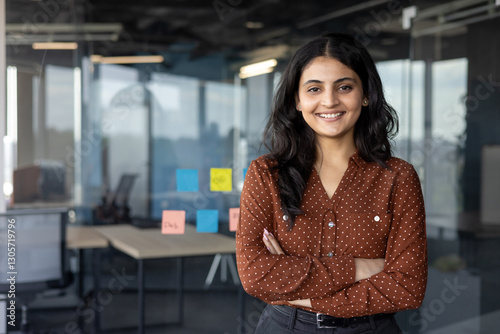 Obraz na płótnie Successful confident businesswoman at workplace inside office, woman with crossed arms smiling and looking at camera, standing near window. Satisfied office worker of company. w salonie