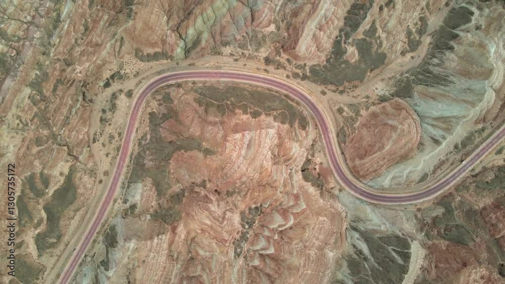 Une route sinueuse traversant un paysage désertique aux couleurs rougeâtres et ocres