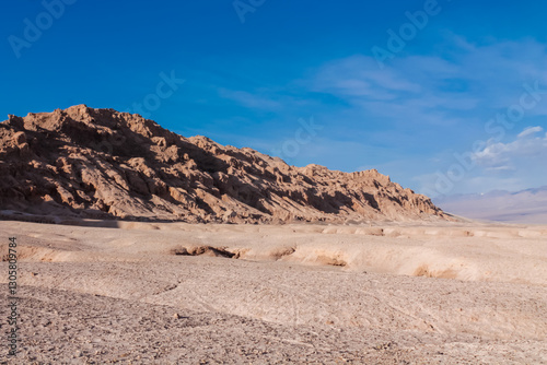 Moon valley famous desert landscape in Chile. Atacama desert tourist sight Valle de la Luna with stunning dry soil arid landscape of red rocks and sand under blue sky  on Altiplano high altitude plain