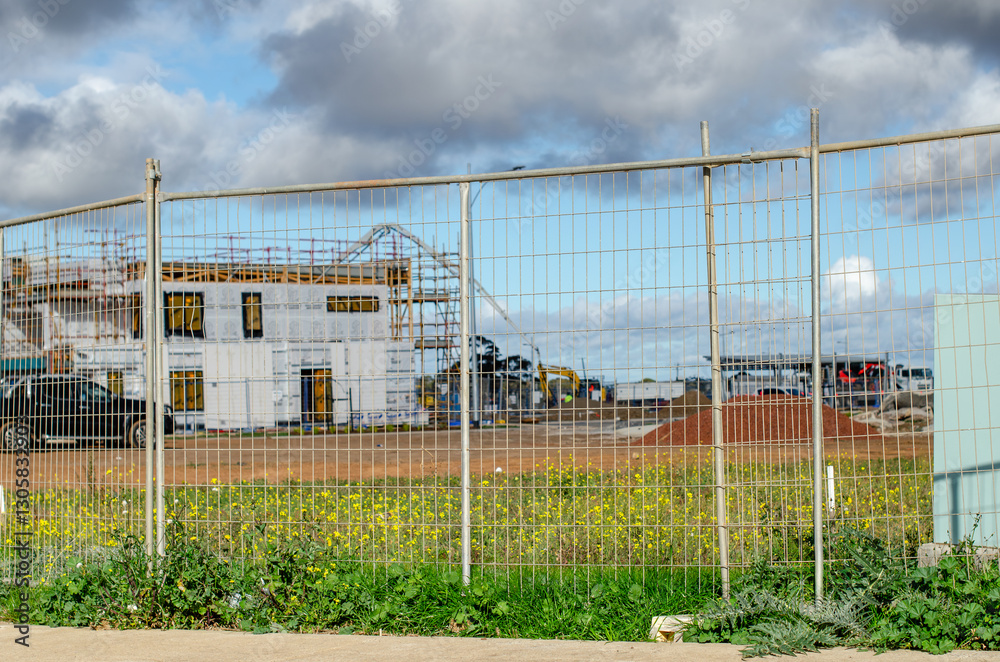 A security fence or a temporary metal mesh barrier at a construction site for a new house and a plot designated for residential neighborhood development in a new estate in Australia. A security fence or a temporary metal mesh barrier at a construction site for a new house and a plot designated for residential neighborhood development in a new estate in Australia.