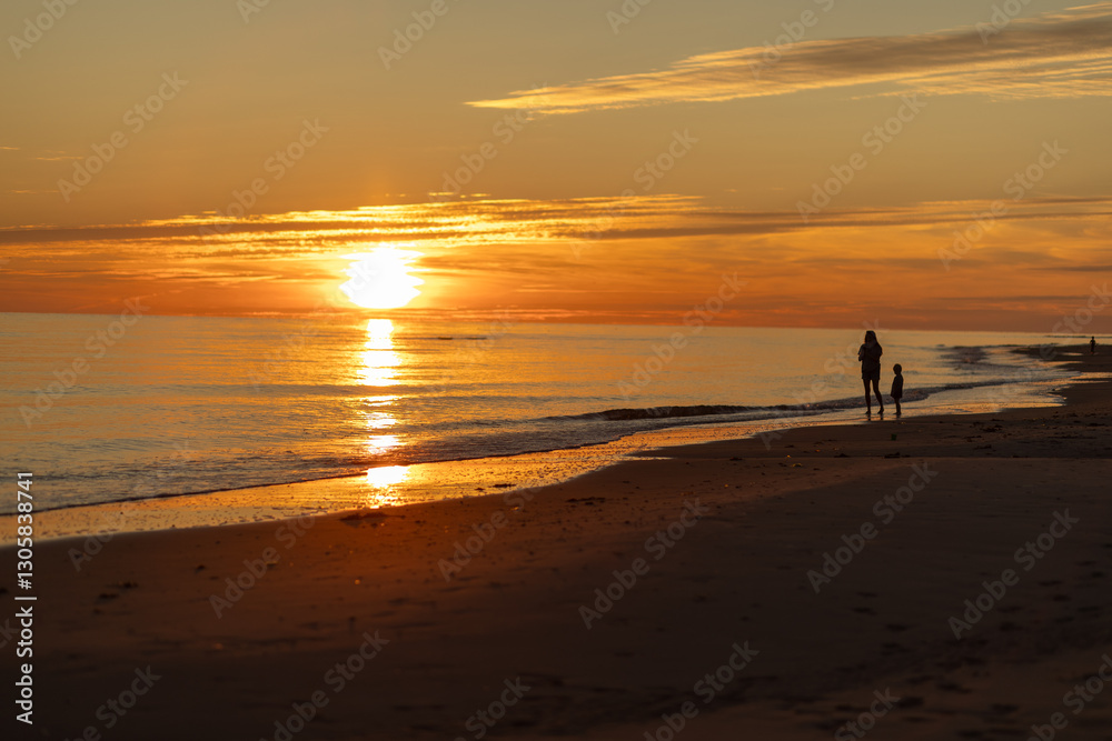 Couple walking along the shore during a tranquil sunset at the beach Couple walking along the shore during a tranquil sunset at the beach