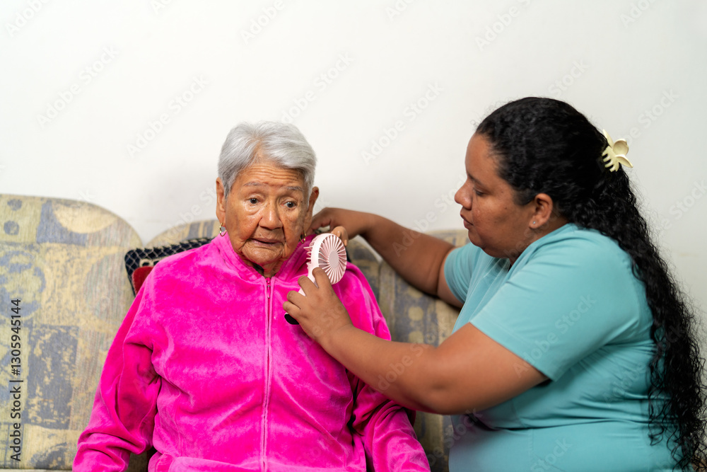 Nurse assisting elderly woman with portable fan at home Nurse assisting elderly woman with portable fan at home