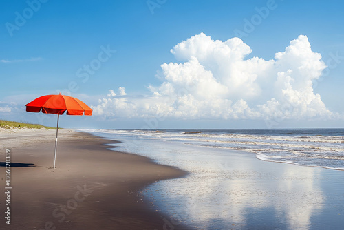 A red beach umbrella stands tall on a sandy beach overlooking a calm ocean with a mountain range in the background..