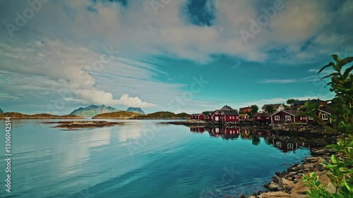 Picturesque nordic landscape. Lofoten islands, Norway.
Blue cloudy sky reflecting on the still sea. View of the red fishermen cabins. photo